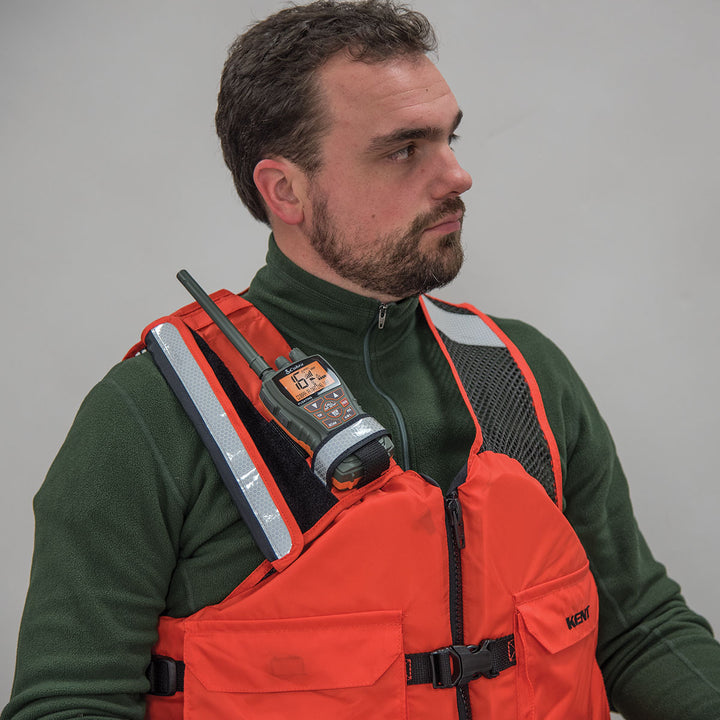 A man in an orange safety vest holds a Radio Pocket VHF radio.