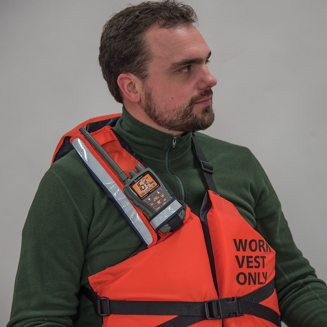Man in green jacket wearing an orange Radio Pocket safety vest with SOLAS-grade reflectors.
